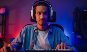 Young Black Man with Headphones Plays Game On Computer