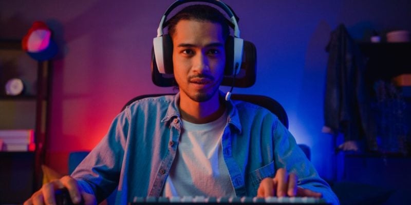 Young Black Man with Headphones Plays Game On Computer