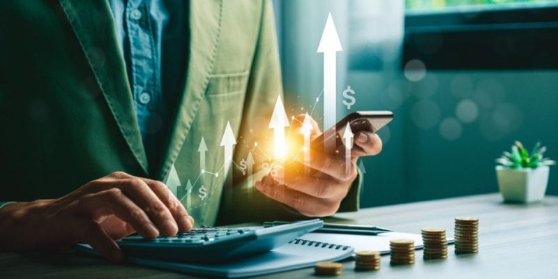 Man Types On Calculator while Holding Mobile Phone