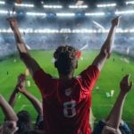 Lit Football Stadium and Cheering Fans with Arms Raised