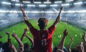 Lit Football Stadium and Cheering Fans with Arms Raised