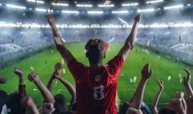 Lit Football Stadium and Cheering Fans with Arms Raised