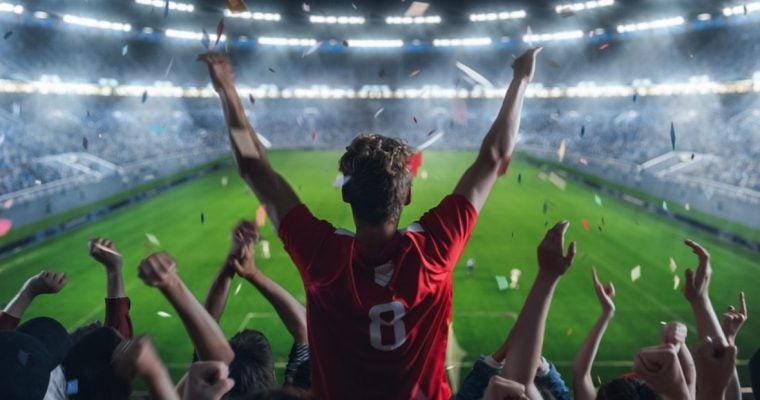 Lit Football Stadium and Cheering Fans with Arms Raised