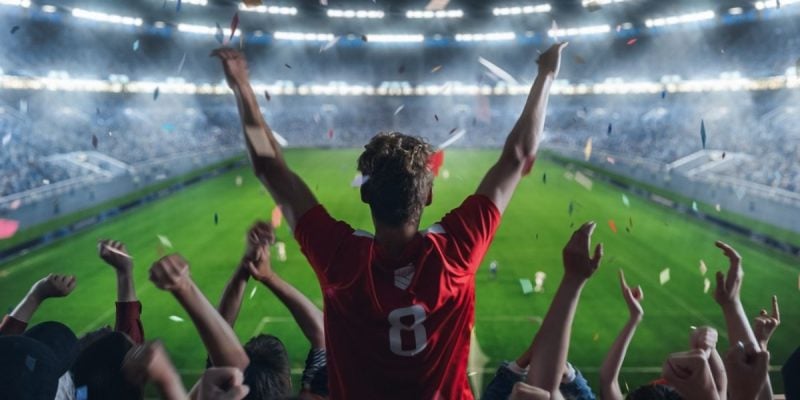 Lit Football Stadium and Cheering Fans with Arms Raised