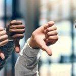 Close Up of Four Hands With Thumbs Down