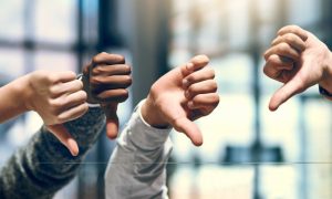 Close Up of Four Hands With Thumbs Down