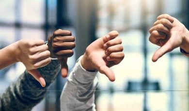 Close Up of Four Hands With Thumbs Down