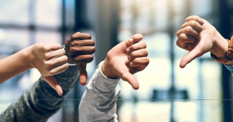 Close Up of Four Hands With Thumbs Down