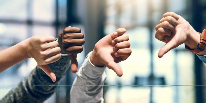 Close Up of Four Hands With Thumbs Down