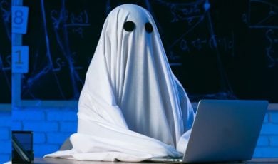 Person in Halloween Ghost Costume Sits At Laptop
