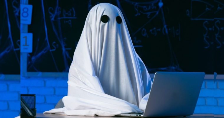 Person in Halloween Ghost Costume Sits At Laptop