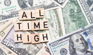 Wood Blocks Read "All Time High" Lying Over Spread Out Cash