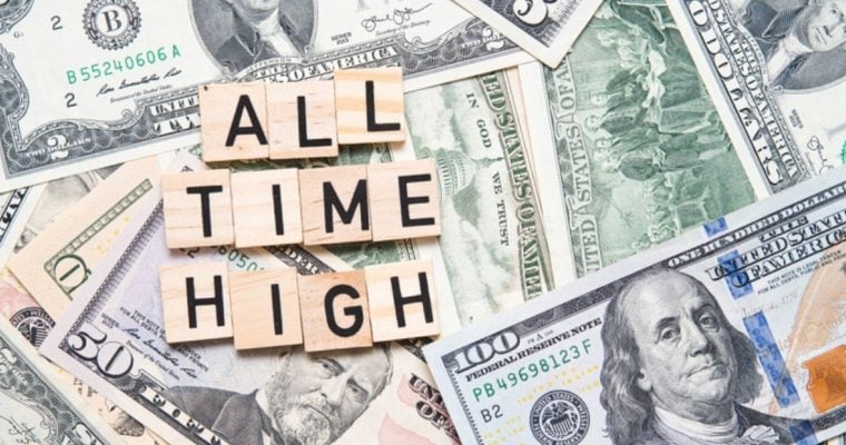 Wood Blocks Read "All Time High" Lying Over Spread Out Cash