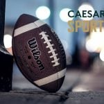 Caesars Sportsbook Logo Over Image of Standing American Football On Ground