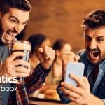 Two Men Celebrate Winning Sport Bet On Cell Phone with Fanatics Sportsbook Logo