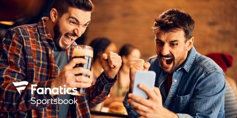 Two Men Celebrate Winning Sport Bet On Cell Phone with Fanatics Sportsbook Logo