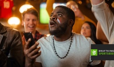 Enthused Black Man Watching Holding Mobile Phone with DraftKings Logo
