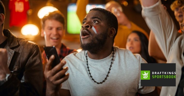 Enthused Black Man Watching Holding Mobile Phone with DraftKings Logo