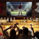 People In Sports Bar Cheer While Watching Football on TV