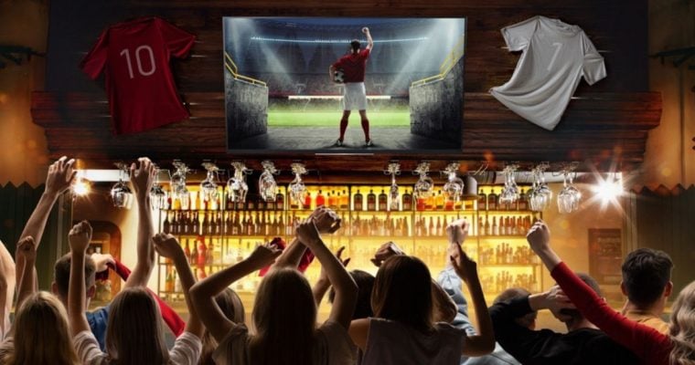 People In Sports Bar Cheer While Watching Football on TV