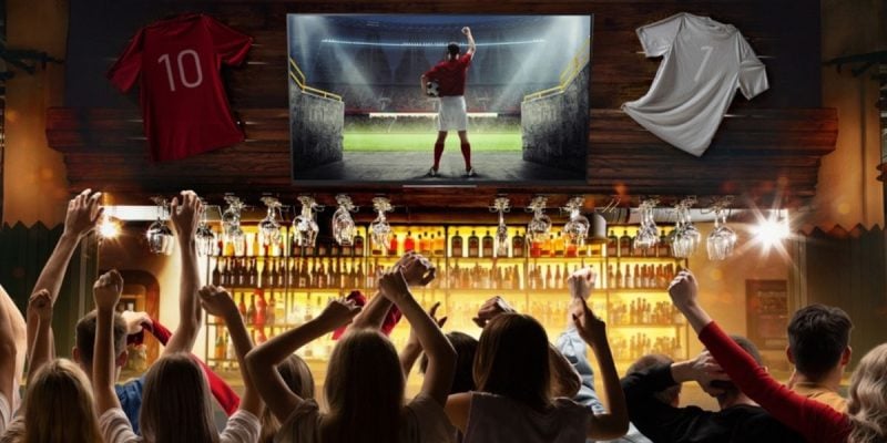 People In Sports Bar Cheer While Watching Football on TV