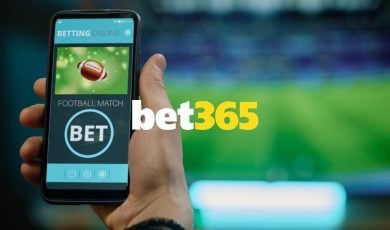 Bet365 logo Centered Over Man Holding Cell Phone and Watching Game on TV