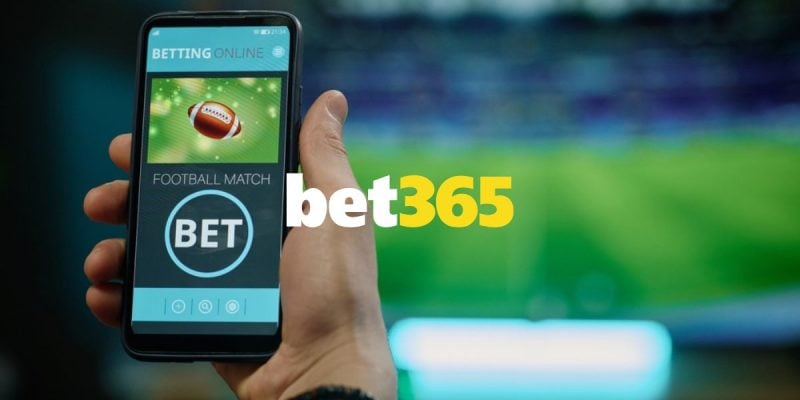 Bet365 logo Centered Over Man Holding Cell Phone and Watching Game on TV