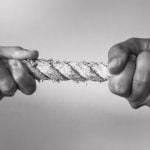 Black & White Close Up Photo of Two Hands Pulling a Rope In Opposite Directions
