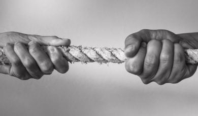Black & White Close Up Photo of Two Hands Pulling a Rope In Opposite Directions
