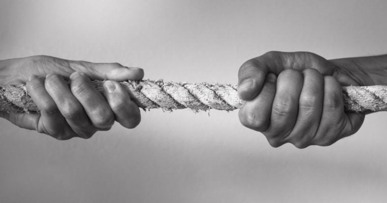 Black & White Close Up Photo of Two Hands Pulling a Rope In Opposite Directions