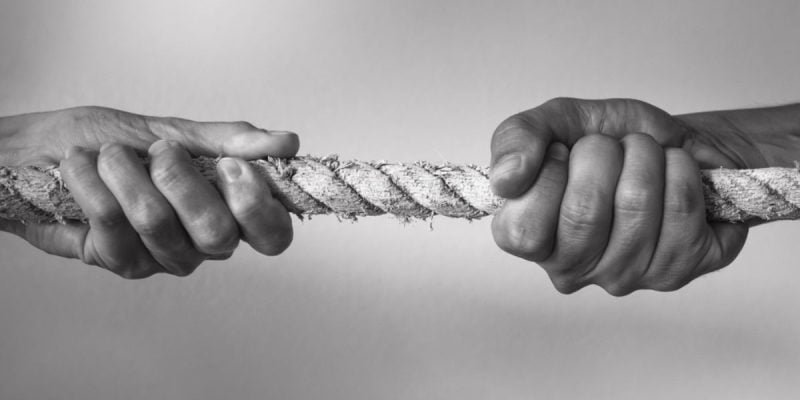 Black & White Close Up Photo of Two Hands Pulling a Rope In Opposite Directions