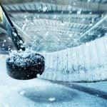 Closeup of Snowy Puck Smashed by Hockey Stick in Arena