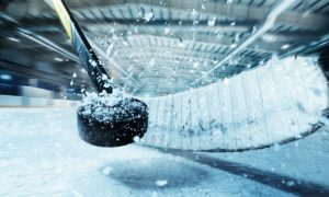 Closeup of Snowy Puck Smashed by Hockey Stick in Arena