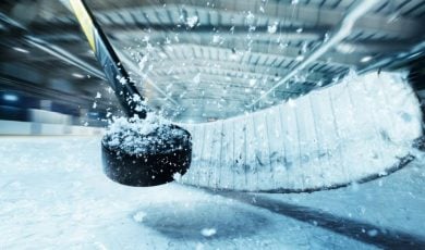 Closeup of Snowy Puck Smashed by Hockey Stick in Arena