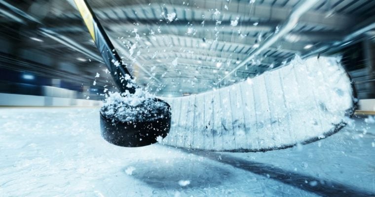 Closeup of Snowy Puck Smashed by Hockey Stick in Arena