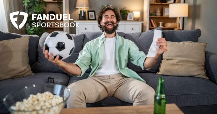 Man Holding Soccer Ball Sits On Couch, Happy About Game Win with FanDuel Logo