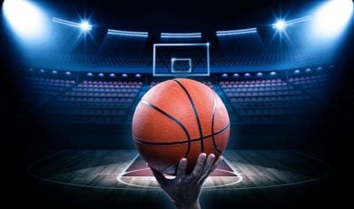 Brightly-Lit Basketball Court with Empty Seats and Man Holding Basketball