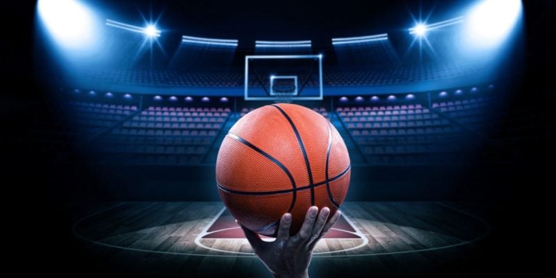 Brightly-Lit Basketball Court with Empty Seats and Man Holding Basketball