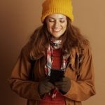 Woman Dressed in Autumn Clothes Holding Cell Phone Smiles