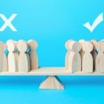 Various People-Shaped Wood Figures Balance On A Scale