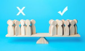 Various People-Shaped Wood Figures Balance On A Scale