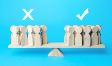 Various People-Shaped Wood Figures Balance On A Scale