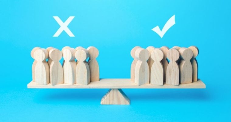 Various People-Shaped Wood Figures Balance On A Scale