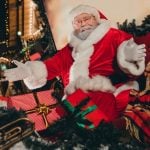 Open-Armed Santa Sits On Christmas Sleigh Full of Wrapped Gifts