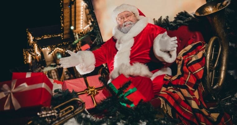 Open-Armed Santa Sits On Christmas Sleigh Full of Wrapped Gifts