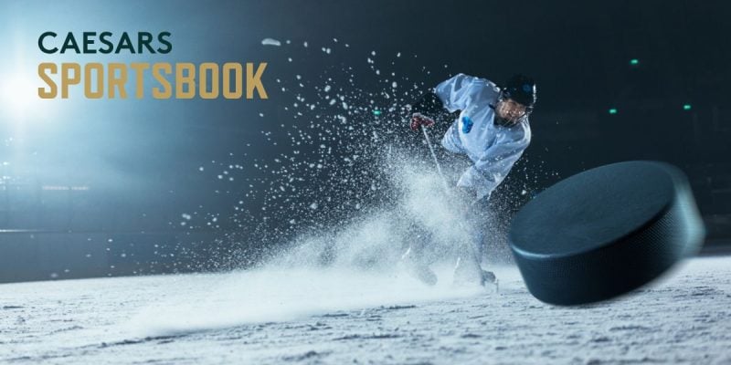 Caesars Sportsbook Logo Over Image of Hockey Player Hitting Puck While Spraying Ice Up