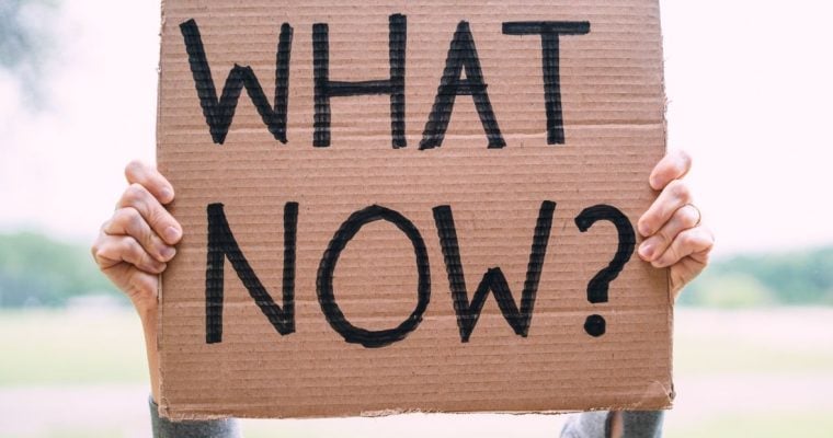 Cardboard Sign Reads "What Now?" In Black