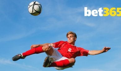 Bet365 Logo Over Image of Soccer Player Mid-Air Kicking Ball Against Blue Sky Background
