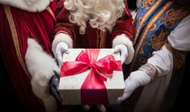 Close Up of Christmas Gift Wrapped with Red Bow Held By Three Santas