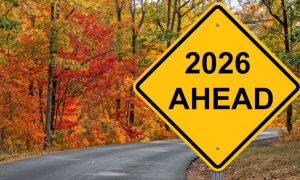 Yellow Caution Sign Reads "2026 Ahead" with Autumn-Colored Trees in Background